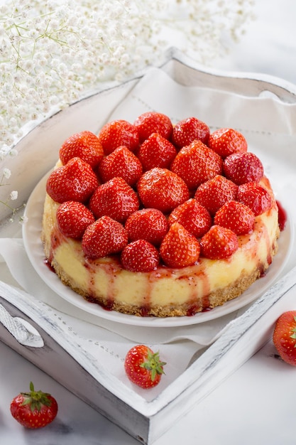 Delicious strawberry cheesecake on white wooden background top view