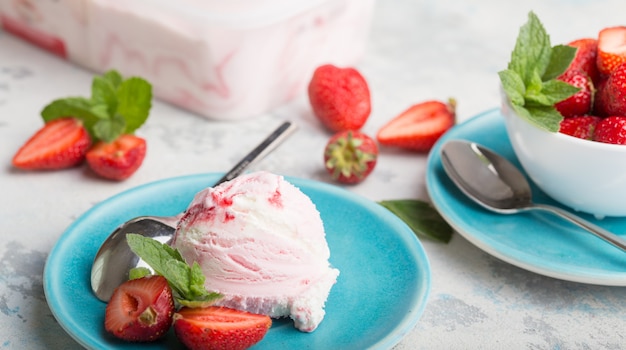 delicious strawberry ice cream scoops balls on blue plate with mint.