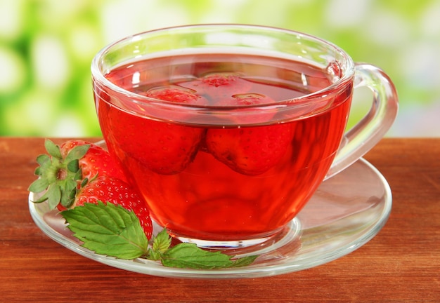 Delicious strawberry tea on table on bright background