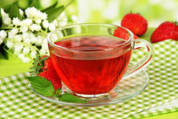 Delicious strawberry tea on table on bright background