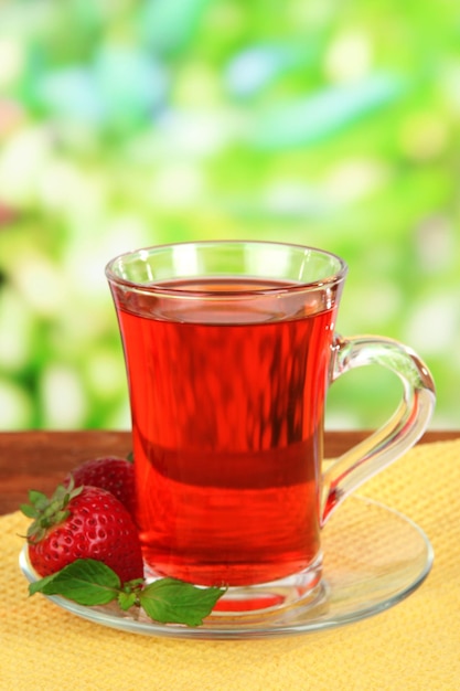 Delicious strawberry tea on table on bright background