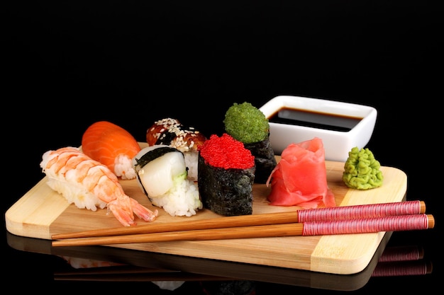 Delicious sushi served on wooden board isolated on black