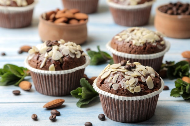 Delicious, sweet chocolate muffins, with almond petals next to the coffee grains on a blue wooden table.