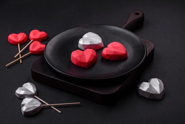 Delicious sweet heart shaped chocolate candies on a dark concrete background