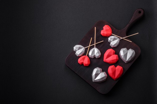 Delicious sweet heart shaped chocolate candies on a dark concrete background