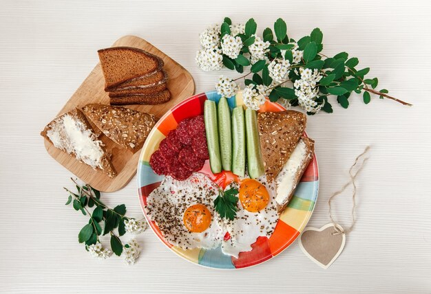 delicious tasty breakfast on colorful plate with white flowers and bread on white background