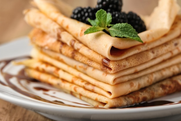 Delicious thin pancakes and berries on plate closeup