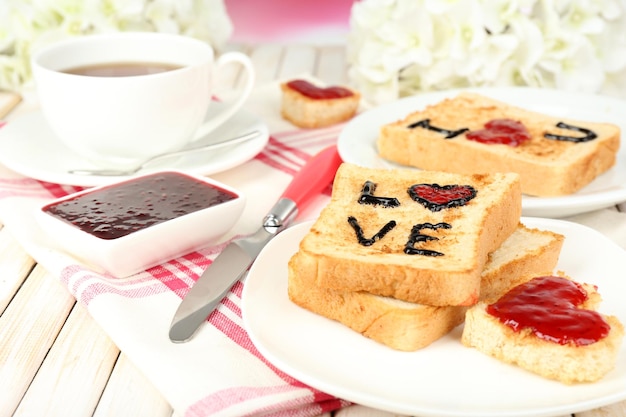 Delicious toast with jam and cup of tea on table close-up