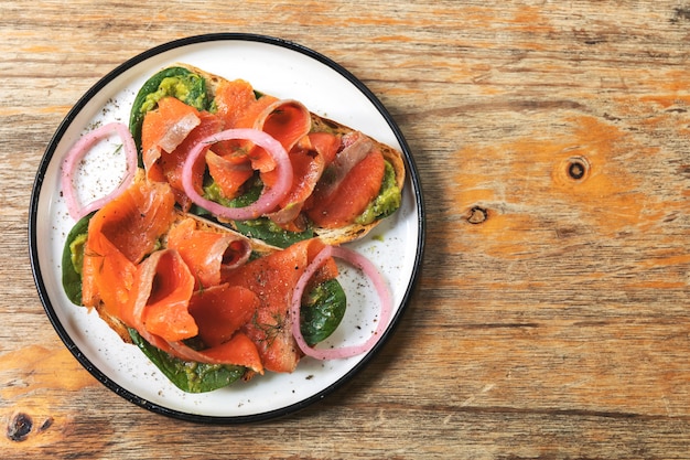 Delicious toasts with smoked salmon, avocado and basil leaves