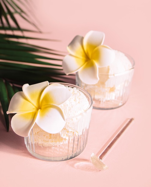 Delicious tropical flavors ice cream sorbet sundae decorated flower plumeria frangipani and palm leaf on the background Summer food concept