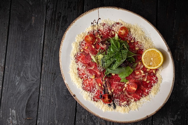 delicious veal carpaccio on a plate on a dark wooden table