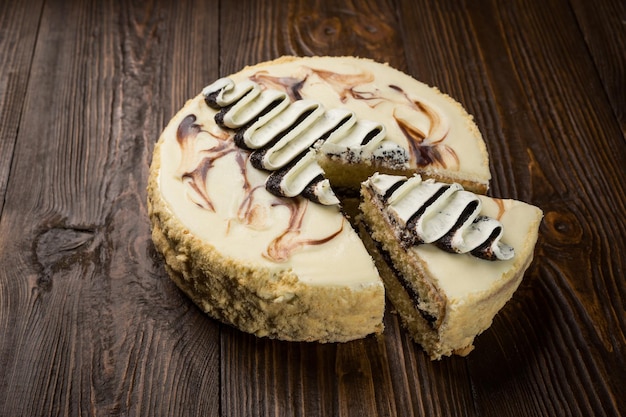 Delicious vegan chocolate cake with cream and poppy seeds on dark wooden background closeup