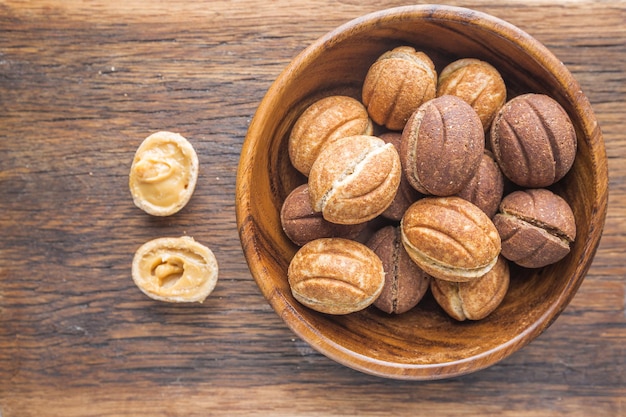 Delicious walnut shaped shortbread sandwich cookies filled with sweet condensed milk on old wooden background, top view