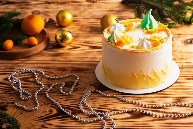 Delicious white cake with orange and spruce twigs on wooden sawn wood christmas decoration atmospheric photo