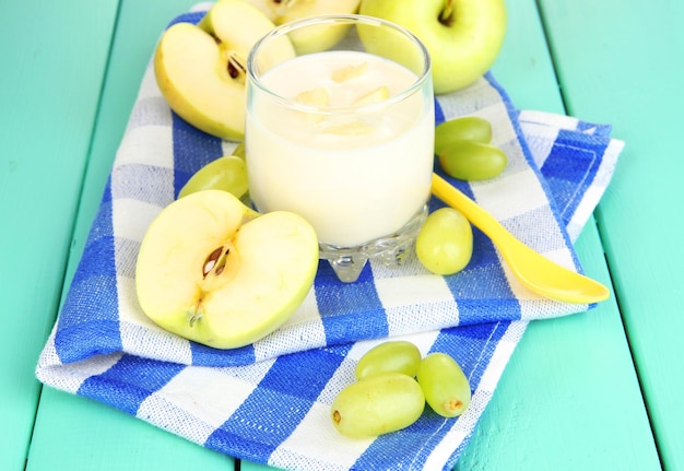 Delicious yogurt in glass with fruit on wooden table closeup