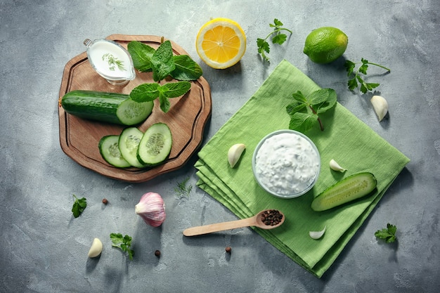 Delicious yogurt sauce in bowl with ingredients on kitchen table