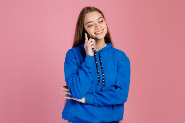 Delighted caucasian woman with happy face calling with mobile phone while squinting eyes in studio