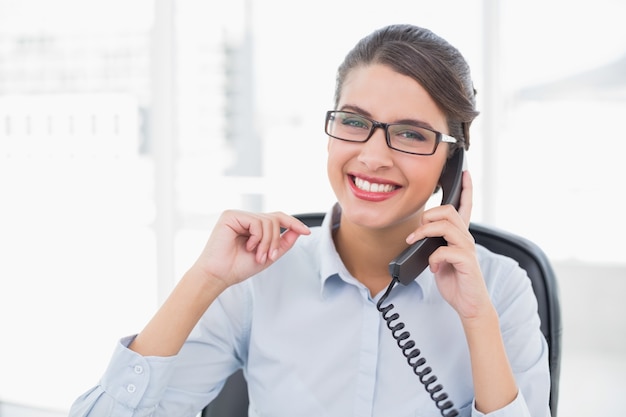 Delighted classy brown haired businesswoman answering the telephone