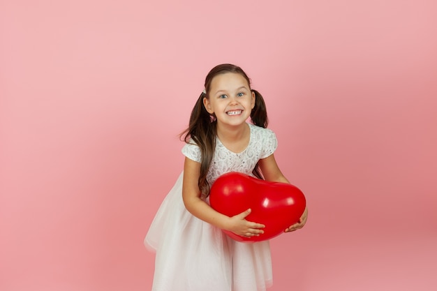 Delighted pleased girl holds a red balloon in the form of a heart