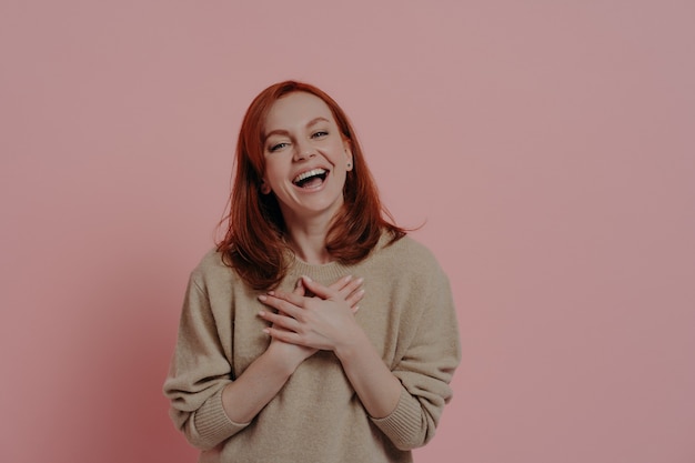 Photo delighted redhaired funny woman laughing out loud isolated on pink background