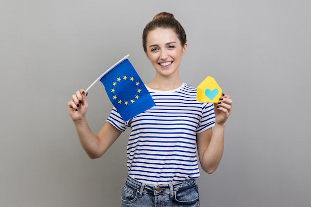 Delighted woman holding flag of European Union travel and rental housing in Europe