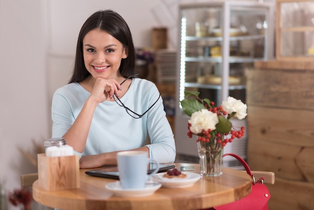 Photo delightful coffee break. attractive satisfied delighted woman smiling and relaxing while visiting a coffee shop.