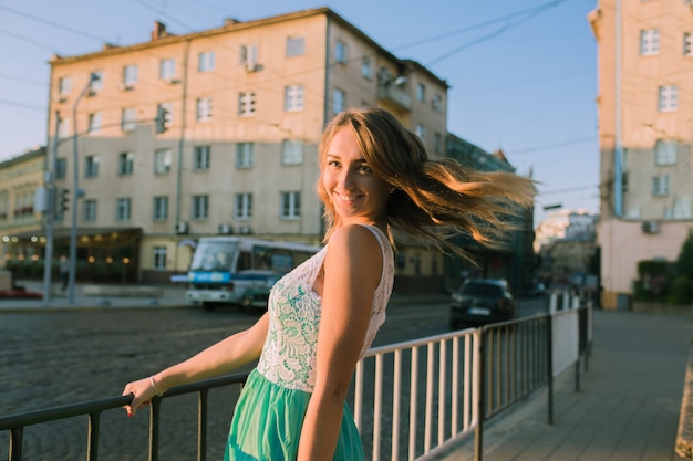 Delightful young  blonde woman with charming smile posing at the sunrise and sun glare