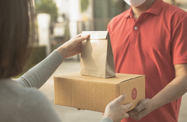 Delivery Asian man wear protective mask in red uniform and ready to send delivering Food bag