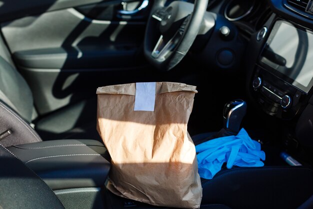 delivery by car. man in protective mask and medical gloves holding a paper box. Delivery service under quarantine, disease outbreak, coronavirus covid-19 pandemic conditions.