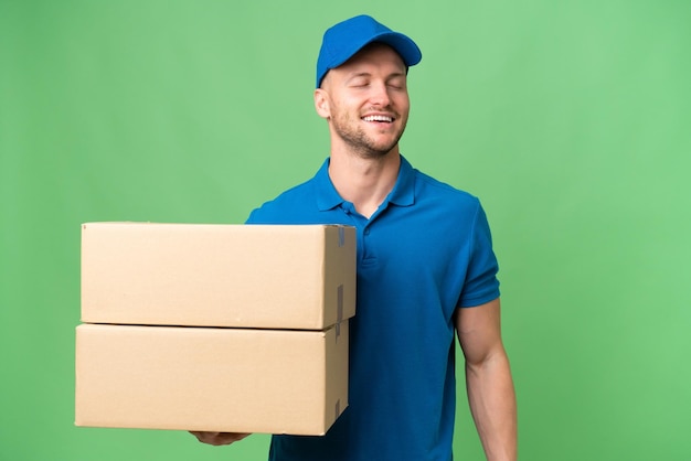 Delivery caucasian man over isolated background laughing