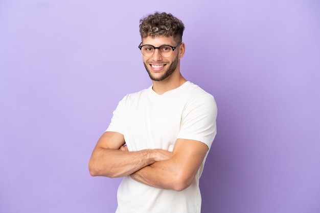 Delivery caucasian man isolated on purple background with arms crossed and looking forward