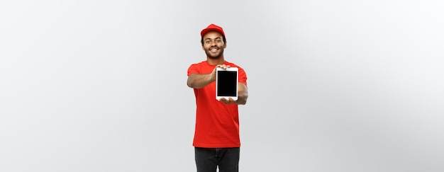 Delivery Concept Portrait of Handsome African American delivery man or courier showing tablet on you to check the order Isolated on Grey studio Background Copy Space