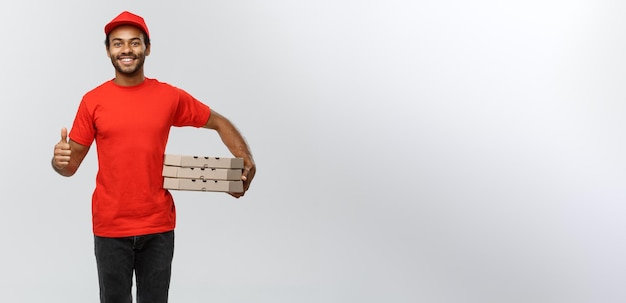 Delivery Concept Portrait of Happy African American delivery man holding box packages and showing thumps up Isolated on Grey studio Background Copy Space