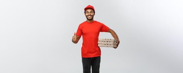 Delivery Concept Portrait of Happy African American delivery man holding box packages and showing thumps up Isolated on Grey studio Background Copy Space