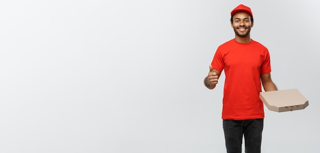 Delivery Concept Portrait of Happy African American delivery man holding a pizza box package and showing thumps up Isolated on Grey studio Background Copy Space