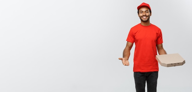 Delivery Concept Portrait of Happy African American delivery man pointing hand to present a pizza box package Isolated on Grey studio Background Copy Space