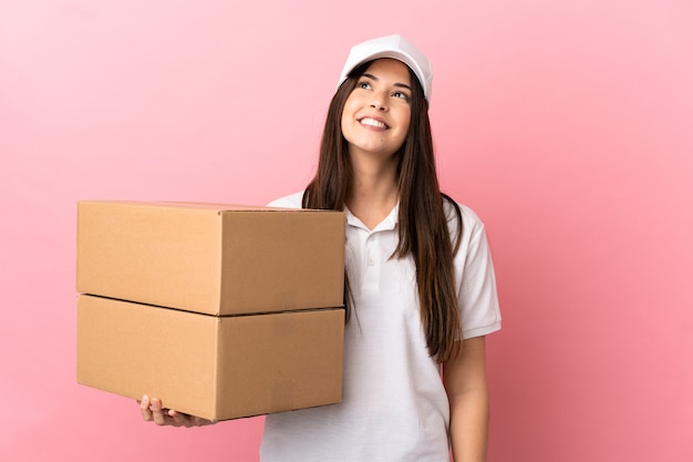 Delivery girl over isolated pink wall thinking an idea while looking up