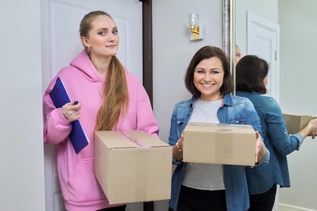 Delivery of goods two women with cardboard boxes near front door of house