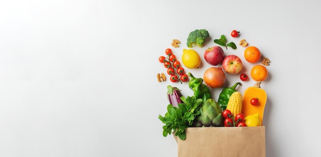 Delivery healthy food background. Healthy vegan vegetarian food in paper bag vegetables and fruits on white, copy space, banner. Shopping food supermarket and clean vegan eating concept.