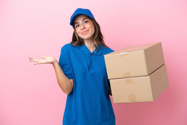 Delivery Italian woman isolated on pink background having doubts while raising hands