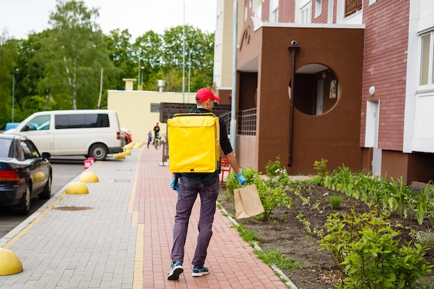 delivery, mail and people concept - happy man delivering food in disposable paper bag to customer home