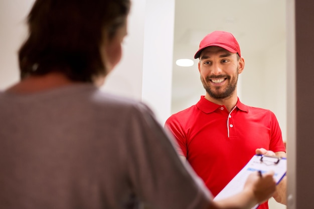 Photo delivery, mail, people and shipping concept - happy man with clipboard and customer signing form at home