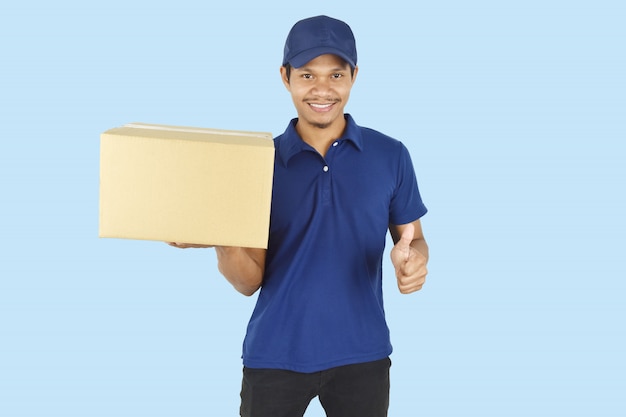 Delivery man holding box and showing thumb up on blue space.