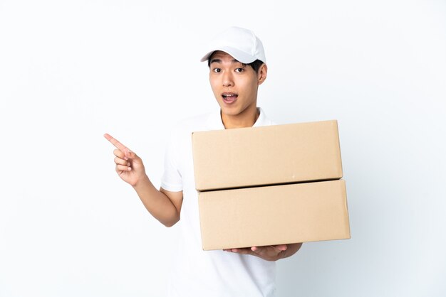 Delivery man isolated surprised and pointing finger to the side