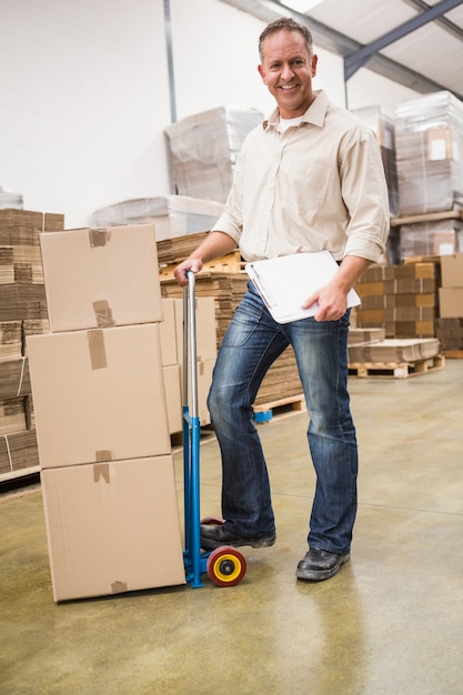 Delivery man leaning on trolley of boxes