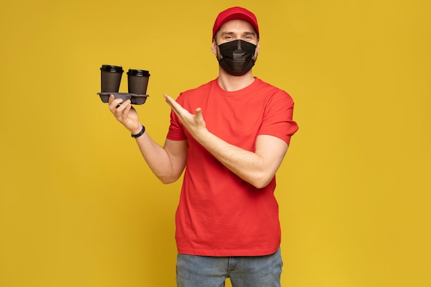 Delivery man in red cap blank t-shirt uniform mask gloves isolated on yellow wall