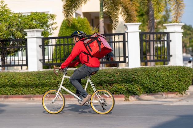 Delivery man in red uniform Cycling to deliver products to customers at home.