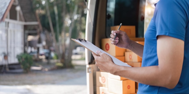 Delivery man signing checklist on clipboard Male courier writing on clipboard and scanning barcode Mature man updating checklist of delivery in van