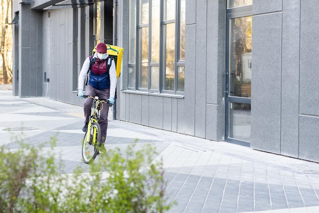 Delivery Man standing with yellow thermo backpack for food delivery near the entrance home with empty space to copy paste.