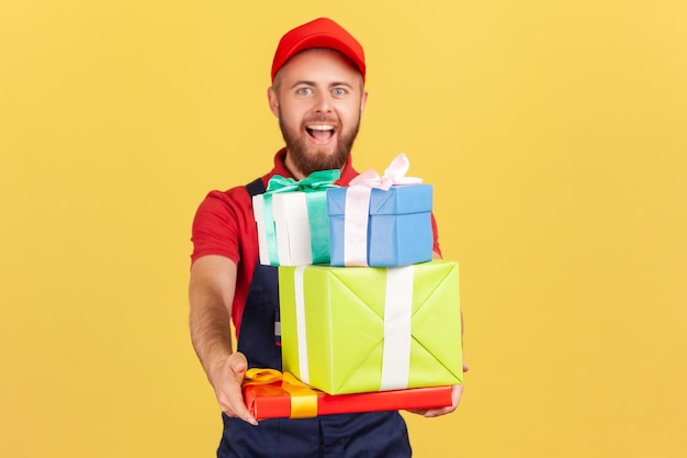 Delivery man wearing uniform and red cap giving many gift boxes to client door to door delivery